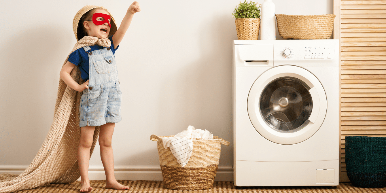 Petit garçon qui fait le super hero devant la machine à laver