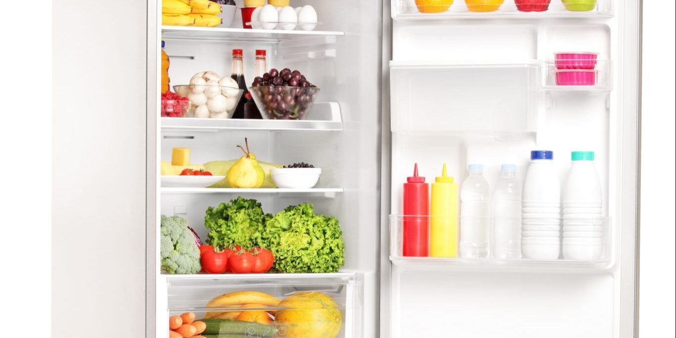 Studio shot of an open fridge full of healthy food products isolated against white background